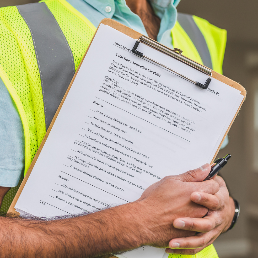 A construction worker in protective gear holding a clipboard with a checklist. The worker is wearing a hard hat, safety vest, and work gloves. The checklist on the clipboard suggests a focus on safety and quality control in the construction environment