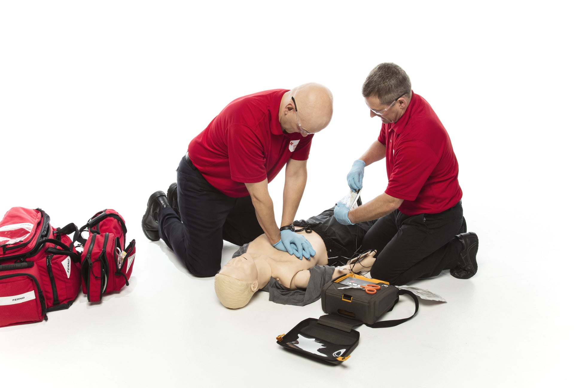 First responders in action, kneeling beside a mannequin and practicing cardiopulmonary resuscitation (CPR). The image shows a team of dedicated individuals delivering chest compressions and rescue breaths as part of their emergency response training. This scene reflects the importance of preparedness in lifesaving techniques.