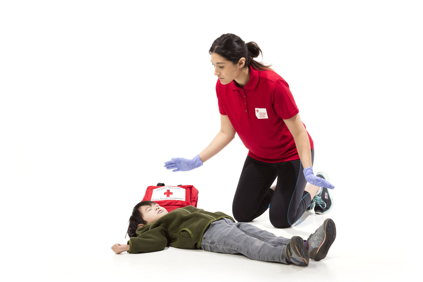 A female first aider, wearing appropriate medical attire, attentively assessing an unresponsive child. The image depicts a compassionate and focused responder checking for vital signs and providing initial care. This scene reflects a caring and professional approach to emergency response.