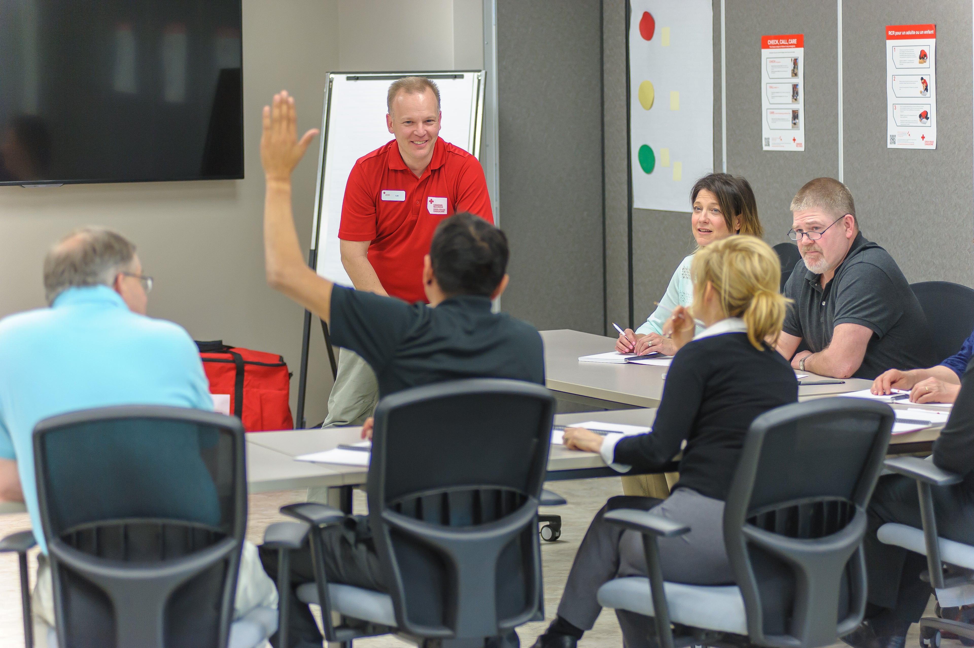 A well-lit first aid classroom with participants seated at desks, engaging in training activities. The room is equipped with educational materials, a first aid kit, and a knowledgeable instructor leading the class. This image captures a learning environment focused on teaching first aid skills and emergency response